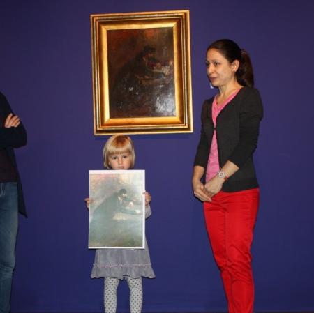 Uczestniczka warsztatów prezentuje swoją pracę pod obrazem "Pisarz Tory" Maurycego Gottlieba.