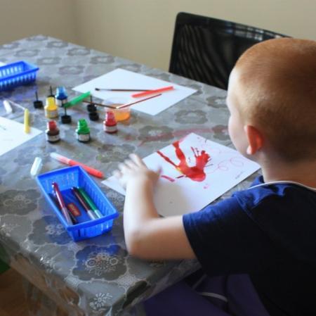 Uczestnicy warsztatów Pałacowa menażeria w sali edukacyjnej tworzą zwierzaki-cudaki za pomocą kolorowego tuszu i flamastrów.
