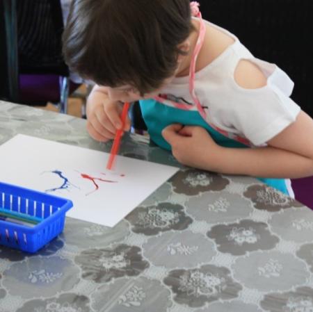 Uczestnicy warsztatów Pałacowa menażeria w sali edukacyjnej tworzą zwierzaki-cudaki za pomocą kolorowego tuszu i flamastrów.