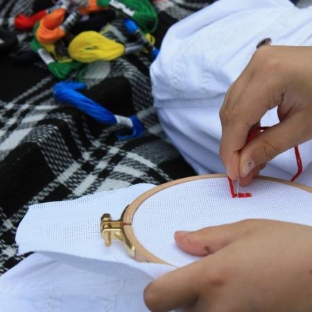 Uczestnik Pałacowych Szarad próbuje swoich sił w haftowaniu.