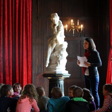 Uczestnicy warsztatu siedzą  przy rzeźbie młodego Kolumba.