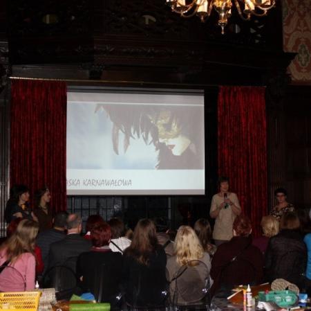 Uczestnicy karnawału podczas oglądania prezentacji o historii maski na sali balowej w Pałacu Herbsta.