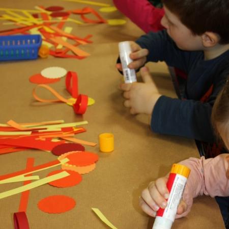 Uczestnicy zajęć wykonujący kwiaty z papieru