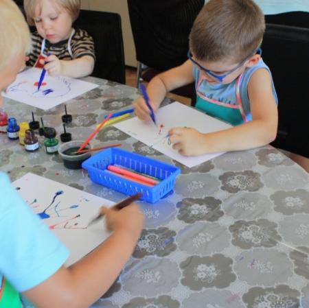 Uczestnicy warsztatów Pałacowa menażeria w sali edukacyjnej tworzą zwierzaki-cudaki za pomocą kolorowego tuszu i flamastrów.