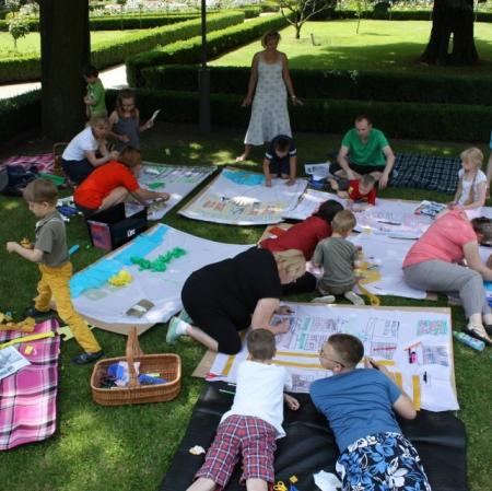 Uczestnicy warsztatów wykonują plan Księżego Młyna na płótnie rozłożonym w przypałacowym ogrodzie - widok z góry.