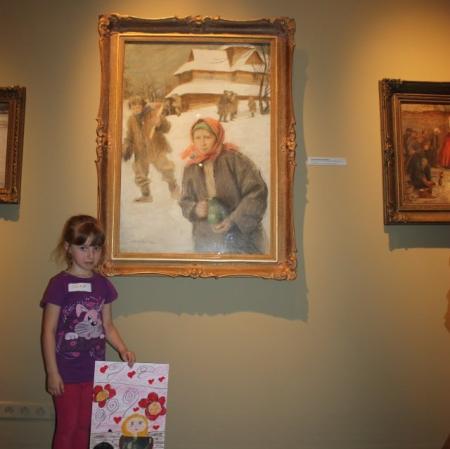 Uczestniczka warsztatu prezentuje swoją pracę pod obrazem "Po wyjściu z cerkwi" Teodora Axentowicza.