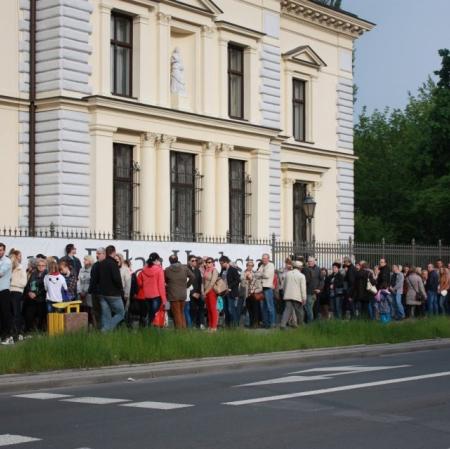 Zdjęcie przedstawia tłum wzdłuż ogrodzenia Muzeum Pałac Herbsta.