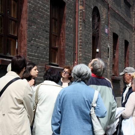 Uczestnicy spaceru "Księży Młyn - miasto samowystarczalne" przed jednym z domów dla robotników fabryki Karola Wilhelma Scheiblera.