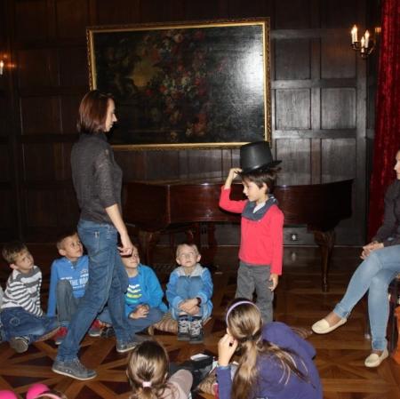 Sala balowa. Scenka rodzajowa- jedna z uczestniczek wita się z mijaną osobą uchylając cylinder.