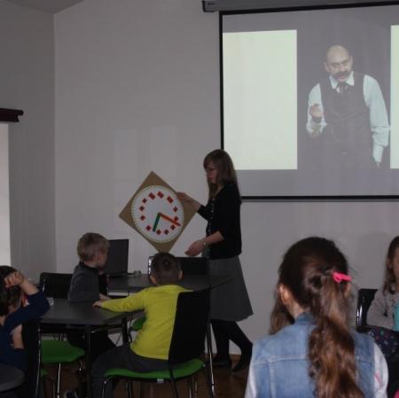 Sala edukacyjna. Prowadząca pokazuje tekturowy zegar.