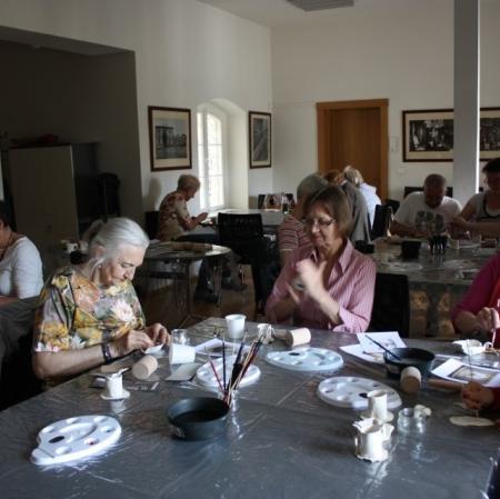 Uczestnicy podczas warsztatów dekorują filiżanki w stylu empirowym