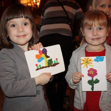 Dwie uczestniczki koncertu prezentują swoje prace plastyczne.