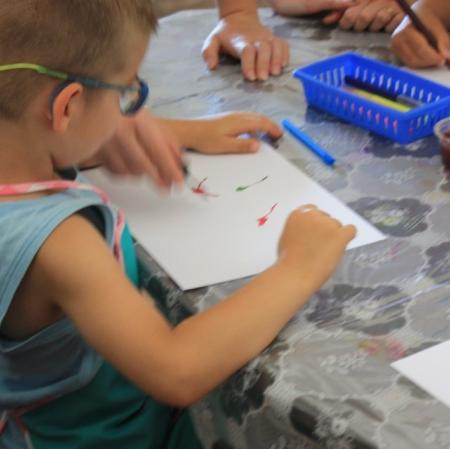 Uczestnicy warsztatów Pałacowa menażeria w sali edukacyjnej tworzą zwierzaki-cudaki za pomocą kolorowego tuszu i flamastrów.