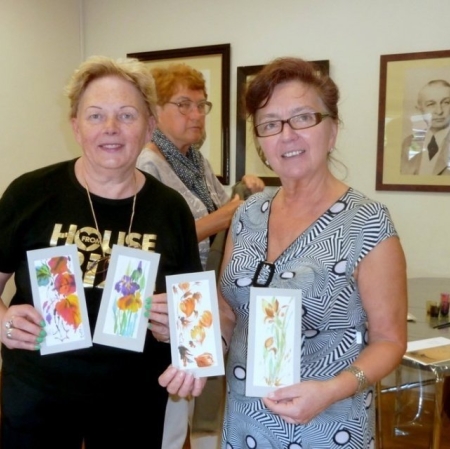 Uczestniczki warsztatów prezentują swoje prace wykonane  farbami do malowania na jedwabiu.