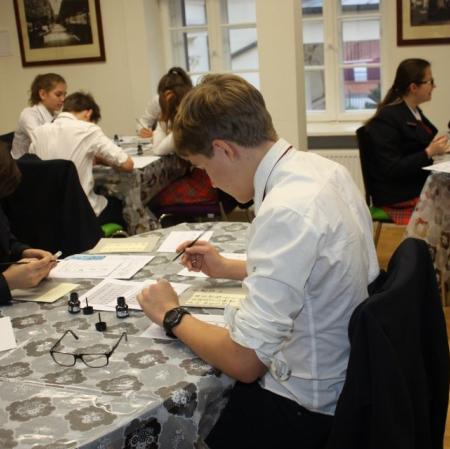 Uczestnicy warsztatów kaligrafują litery japońskiego alfabetu.