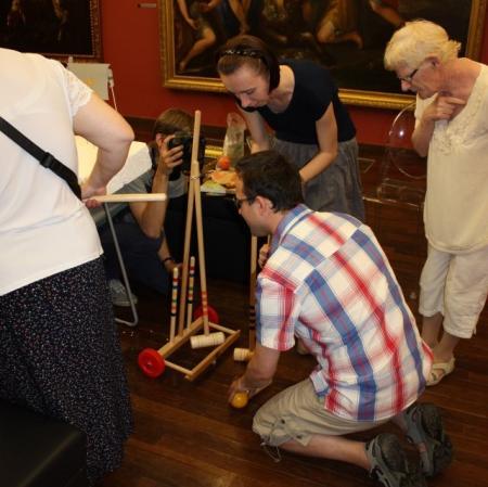 Uczestnicy warsztatu "Pałac Herbst w kilku odsłonach" poznają sprzęt do gry w krokieta.