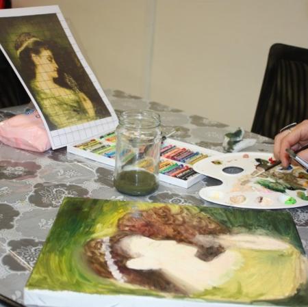 Zbliżenie na dłonie uczestniczki oraz powstającą prace malarską.