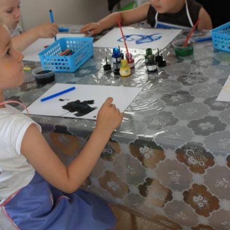 Uczestnicy warsztatów Pałacowa menażeria w sali edukacyjnej tworzą zwierzaki-cudaki za pomocą kolorowego tuszu i flamastrów.