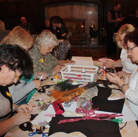 Uczestniczki karnawału wykonują swoje własne maski za pomocą przygotowanych materiałów na sali balowej w Pałacu Herbsta.