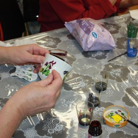 Uczestniczka warsztatów malująca filiżankę - zbliżenie.