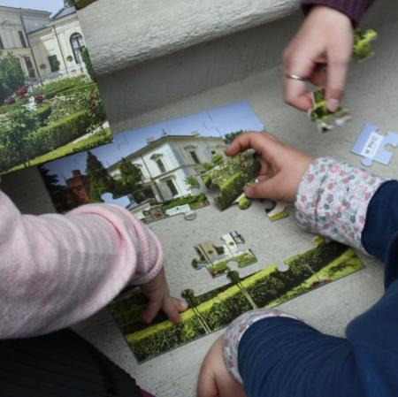 Uczestnicy I Edycji Konkursu Plastycznego "Pocztówka z Pałacu Herbsta" podczas układania puzzli  w pałacowej oranżerii.