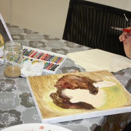 Zbliżenie na dłonie uczestniczki oraz powstającą prace malarską.