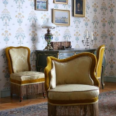 Zdjęcie: wnętrze, w którym stoją obite jasną tkaniną krzesła przy biurku oraz fotel.