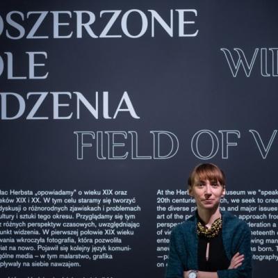 Kobieta stojąca na tle ściany z napisem Poszerzone pole widzenia