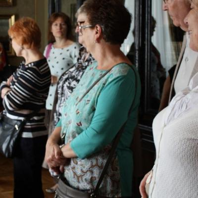 Zdjęcie przedstawia wnętrze ekspozycji wystawowej, w której stoi kilka osób.