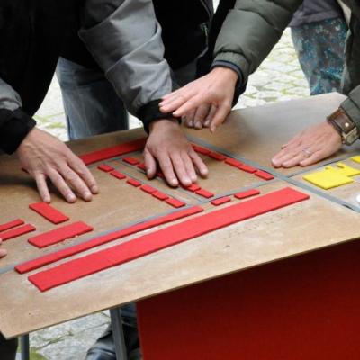 Zbliżenie na ręce kilku osób, dotykają tyflografiki z planem osiedla