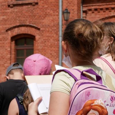 Grupa dzieci odwróconych tyłem, patrzą na budynek z czerwonej cegły.JPG