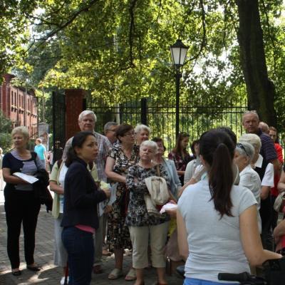 Zdjęcie: liczna grupa dorosłych stoi wśród zielonych drzew.