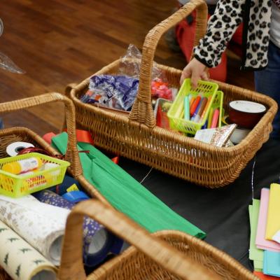 W centrum wiklinowe koszyki, w których znajdują się materiały plastyczne, takie jak: kolorowe bibuły i kartki, wstążki, flamastry i kleje.