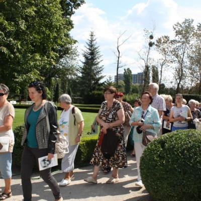 Uczestnicy spaceru w ogrodzie przy Pałacu Herbsta