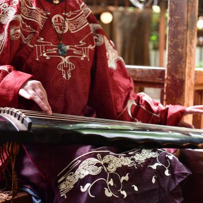 Zbliżenie na azjatycki instrument muzyczny leżący na kolanach kobiety ubranej w czerwone kimono.
