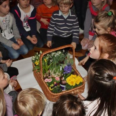 Uczestnicy jednego z koncertów siedzą wokół koszyka z różnymi gatunkami wiosennych kwiatów.