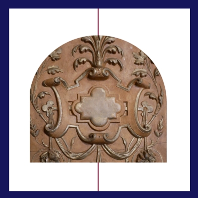 Półokrągły relief z jasnobrązowego kamienia przedstawia symetryczny ornament roślinny. W centrum znajduje się ozdobny motyw w kształcie czterolistnej rozety, otoczony wijącymi się liśćmi i kwiatami. Dekoracja jest bogata, stylizowana i harmonijnie podzielona na dwie części.