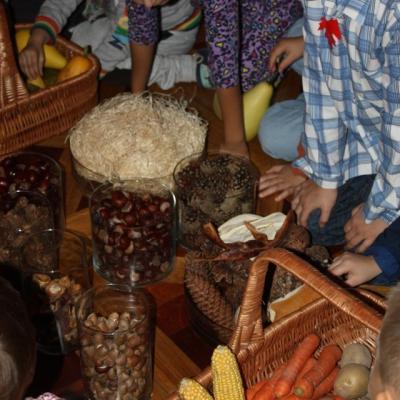 na podłodze w koszyku po prawej marchewki, dynie, kukurydza, a także w słoikach kasztany, szyszki