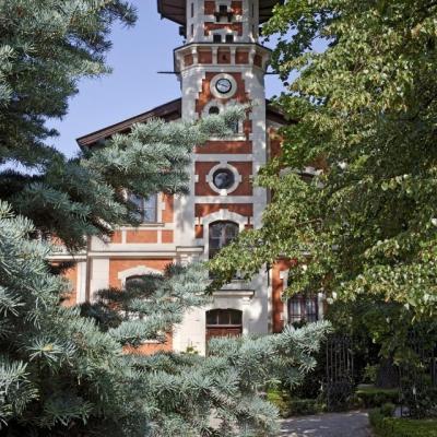 Za zielonymi drzewami wieża dawnej pałacowej powozowni